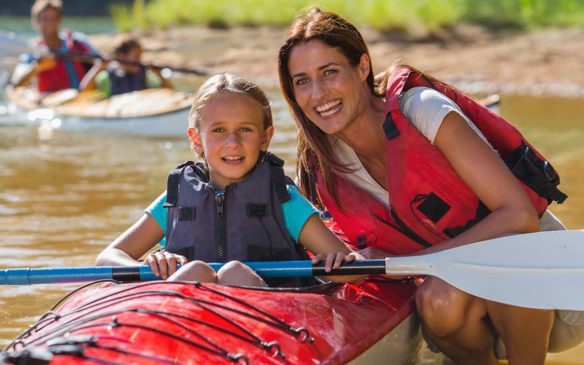 a family teaching their children to kayak on the Yadkin River